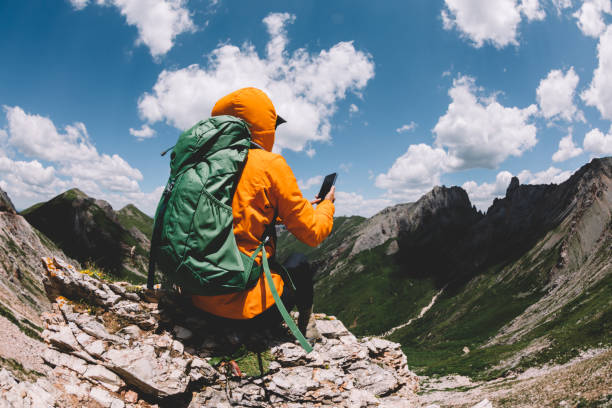 istock Successful woman backpacker using smart phone on alpine mountain top 1337753787