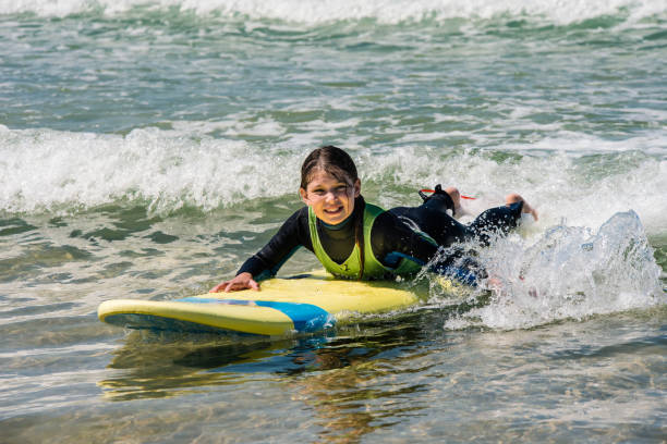 istock cute smiling girl learning to surf the waves 1337755539