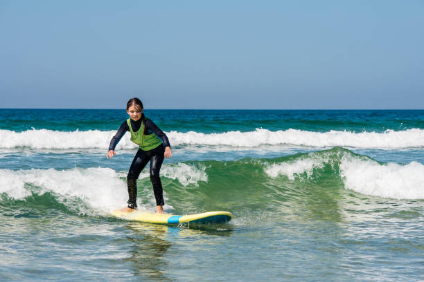 istock cute smiling girl learning to surf the waves 1337755906
