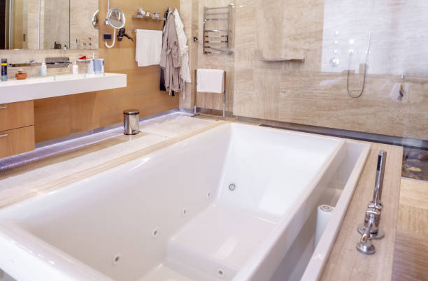 White hot tub in functional marble bathroom with mirror and walk-in shower