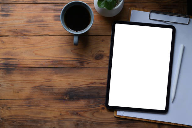 istock Top view digital tablet, clipboard, and coffee cup on wooden table. 1337758411