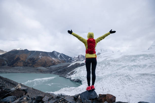 une femme traileuse à succès ouvre les bras aux montagnes de neige fossiles des glaciers d’hiver - cross coat photos et images de collection