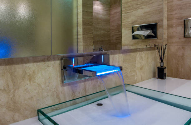 LED faucet with waterfall spout over glass sink in stylish bathroom stock photo