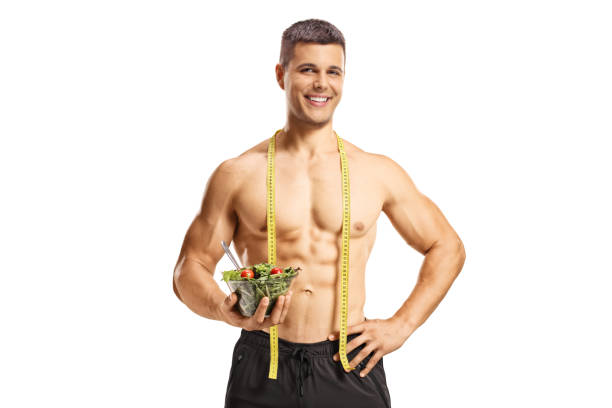 Shirtless muscular man holding a salad bowl and smiling at camera Shirtless muscular man holding a salad bowl and smiling at camera isolated on white background Bodybuilders Eat stock pictures, royalty-free photos & images