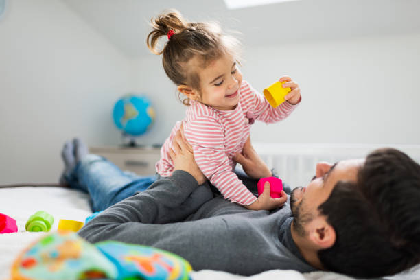 istock Father and baby girl playing on bed 1337761495