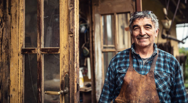 istock Aged craftsman standing and smiling in front of his rustic workshop. 1337761756