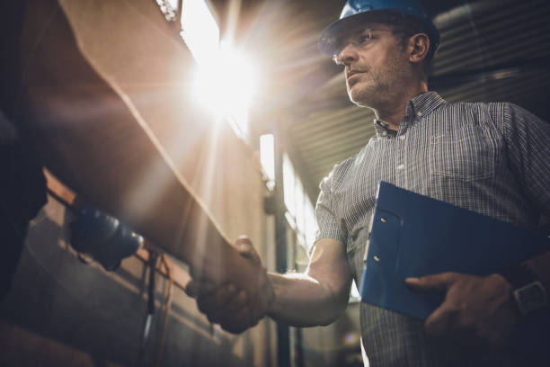 istock Below view of serious inspector shaking hands with unrecognizable person. 1337764378