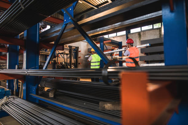 istock Two metal workers cooperating while carrying steel in a factory. 1337765832