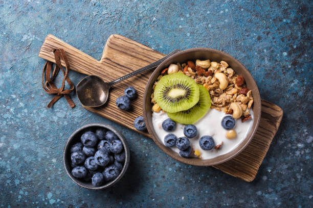 bol avec granola, yogourt, kiwi frais, myrtille et noix - healthy eating breakfast ripe fruit photos et images de collection