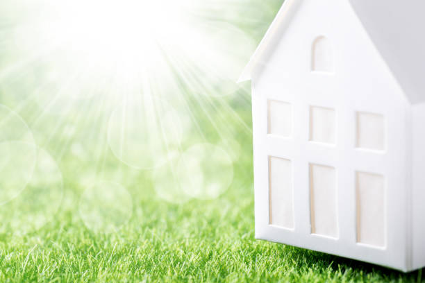 istock Model of white paper house on green grass background 1337768360