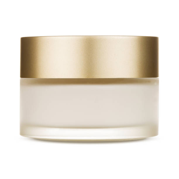 A round glass jar for cosmetics with a gold lid.