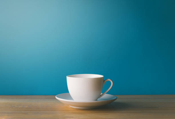 istock White coffee cup on wooden desk with blue background 1337774452