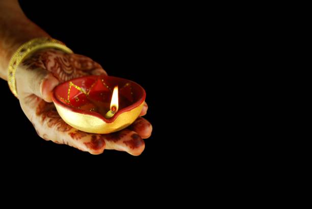 fotografia adequada para o festival indiano diwali, teej e karwachauth, deepawali, mão de uma mulher com henna ou mehndi - lighting equipment illuminated isolated on black part of - fotografias e filmes do acervo