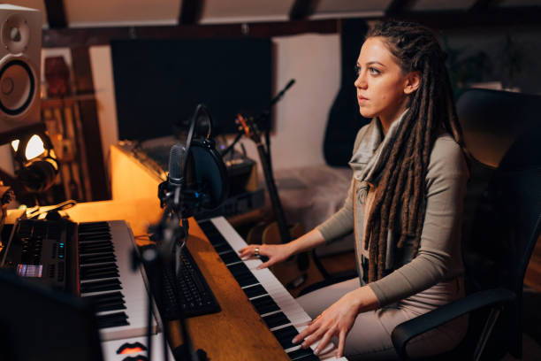 istock Sound engineer, in her sound recording studio, using the electric music keyboard, while working on audio production 1337777077