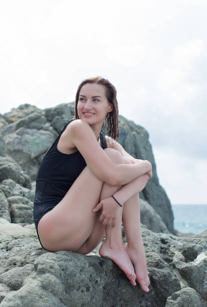 istock Attractive girl resting on rocky seashore 1337778229