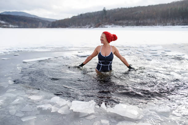 vorderansicht der aktiven seniorin im badeanzug im winter im freien, kältetherapiekonzept. - ice winter white women stock-fotos und bilder