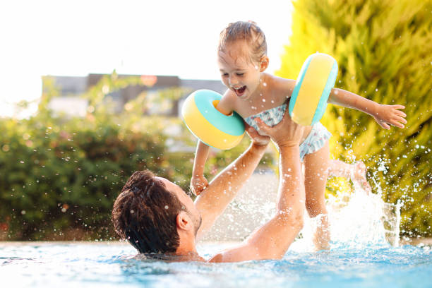 istock Cute little girl having fun with parents in pool 1337780904