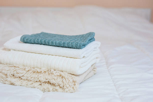istock home textiles. A stack of towels lies on a white bed 1337781100