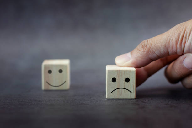 istock Closeup customer hand choose sad face and blurred sad face icon on wood cube 1337786738