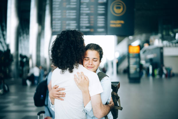 Young couple at the airport departure area saying goodbye Young family couple at the airport departure area saying goodbye or hello, embracing each other with smile. Arrival and reunion awaiting after travel airport hug stock pictures, royalty-free photos & images