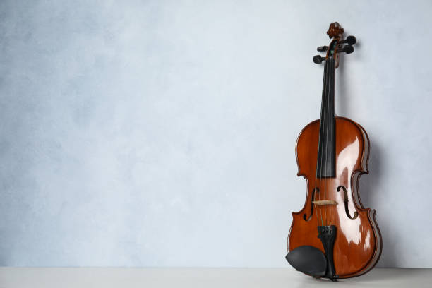 istock Beautiful violin on table near light blue wall. Space for text 1337794503