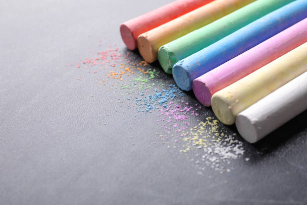 istock Pieces of color chalk on blackboard, space for text 1337795450