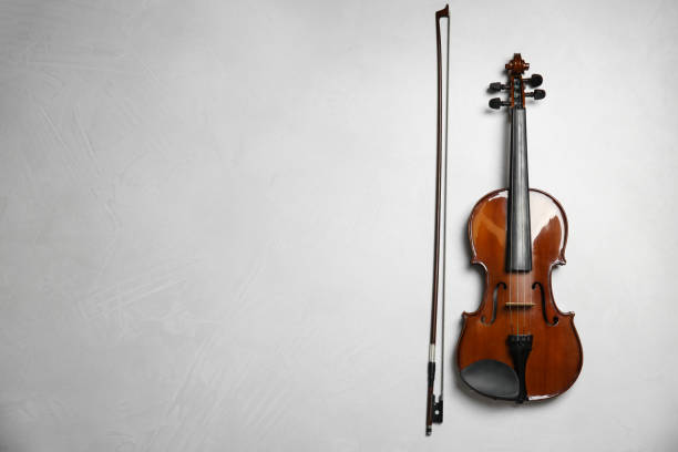 istock Beautiful violin and bow on grey stone table, flat lay. Space for text 1337795452