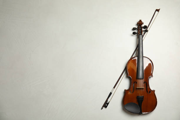 istock Beautiful violin and bow on grey stone table, flat lay. Space for text 1337795453
