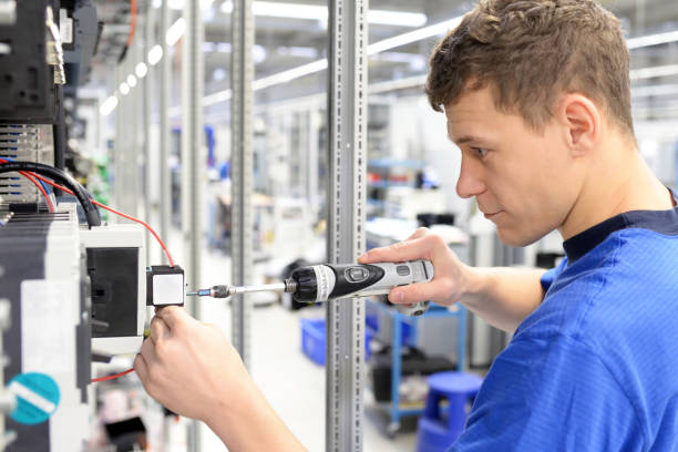 jovem aprendiz trabalhador em uma empresa industrial montando componentes eletrônicos na engenharia mecânica de uma fábrica moderna - equipamento elétrico equipamento industrial - fotografias e filmes do acervo