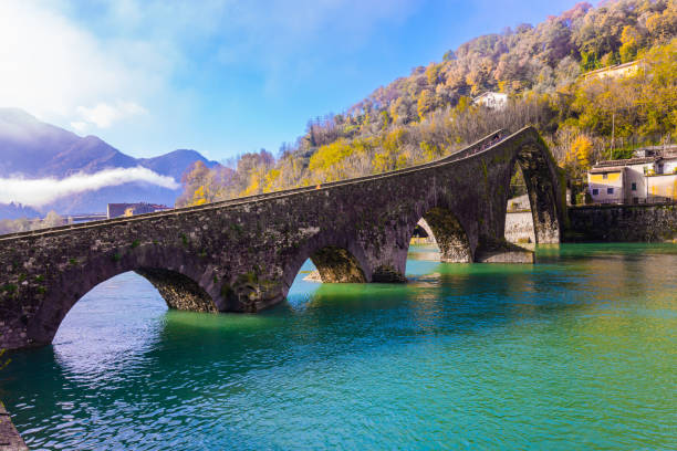 The old name is Devil's Bridge The old name of the bridge is Devil's Bridge. Italy, Lucca. The emerald cold water of the river reflects the ancient asymmetrical arches of the bridge. The Serchio River. lucca stock pictures, royalty-free photos & images