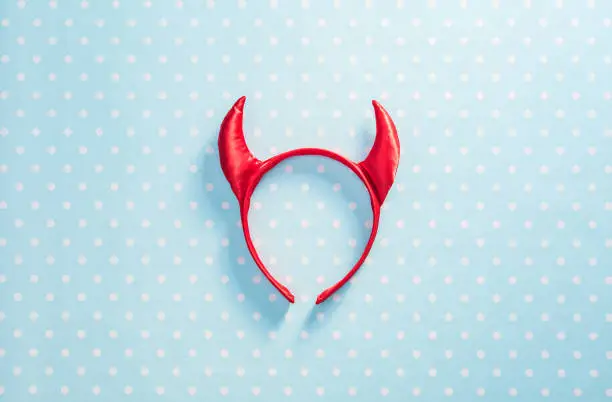 Photo of Red devil horns on a headband hoop. Halloween texture background