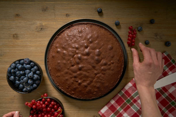 istock Woman decorates handmade chocolate cake with blackberries and red currants. 1337809335