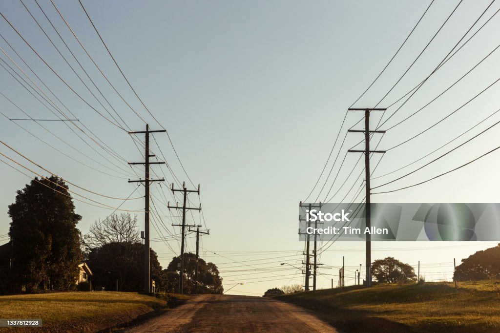 Electric Poles And Cables Along Country Road Electric poles with many cables located along rural country road with clear blue sky in background. Power Line Stock Photo