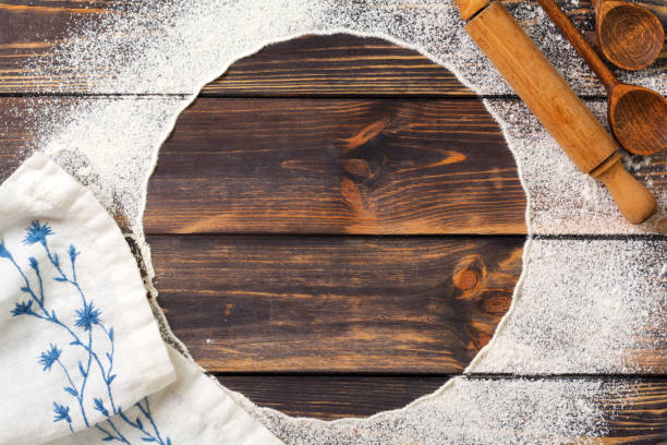 Flour scattered in the form of a circle, rolling pin and white linen napkin on an old wooden background. Place for text. Background for baking stock photo