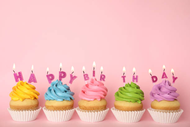 istock Birthday cupcakes with burning candles on pink background. Space for text 1337815058