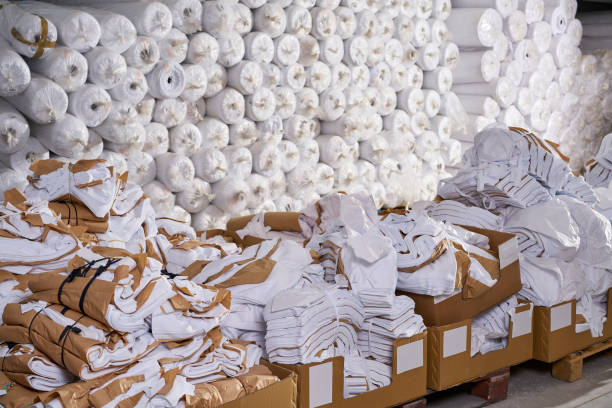 Factory workers in hi vis clothing pushing heavy load of rolled up carpets