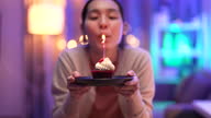 istock Woman blowing out candles on cake 1337824248
