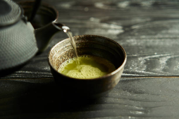 японский органический зеленый чай маття в чашке на фоне черного дерева. - japanese tea cup стоковые фото и изображения