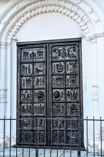 Magnificent bronze door to enter the temple, multi-figured composition, religious subjects, delicate handwork, scenes from the lives of saints, beauty and charm, religious signs and symbols, Orthodox symbols, German work, history and culture, sunlight, summer, work of art, Museum exhibit.