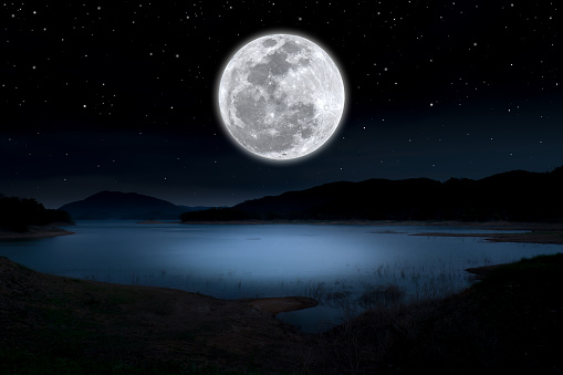 Full moon on sky over lake in the night.