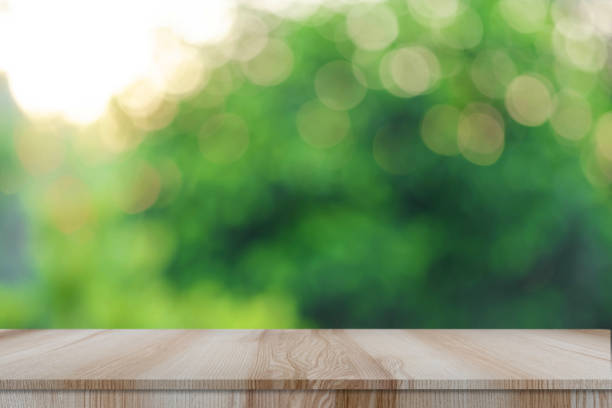 istock Empty modern brown wooden table with bokeh green nature background 1337833358