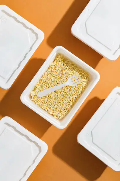 Raw instant noodles in a package on an orange background