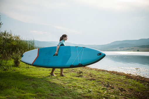 Young Woman Going To The Mountain Lake Carrying Paddle Board