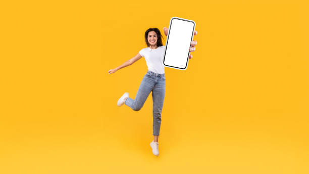 istock Happy woman showing white empty smartphone screen and jumping 1337841384