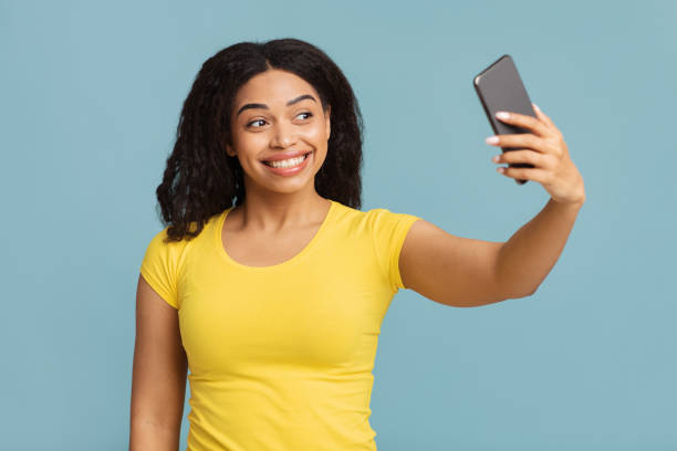 istock Positive black lady making selfie on smartphone, posing and having fun over blue studio background 1337841742