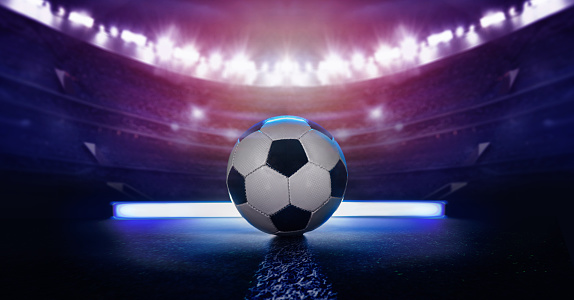 football or soccer ball against black background in neon light