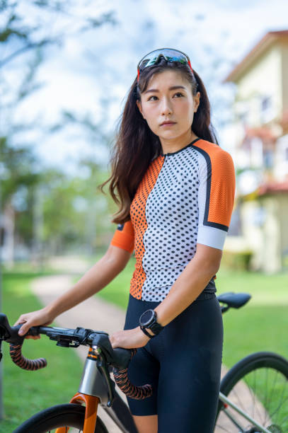 porträt asiatische chinesische radfahrerin schaut mit cooler haltung im öffentlichen park mit ihrem rennrad-radfahren weg - cyclist cycling road women stock-fotos und bilder