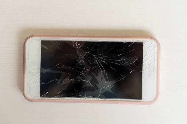 istock Modern mobile smartphone with broken screen on white wooden table 1337843258