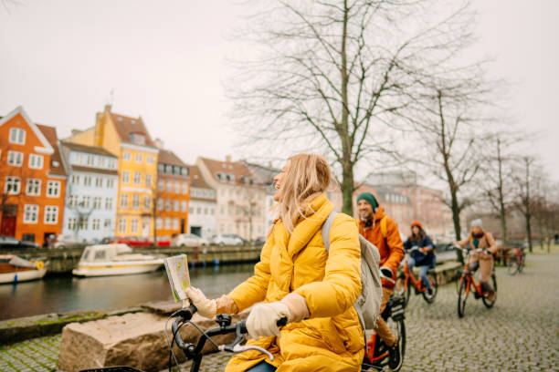 町を自転車に乗った旅行ガイドと彼女のグループ - denmark ストックフォトと画像