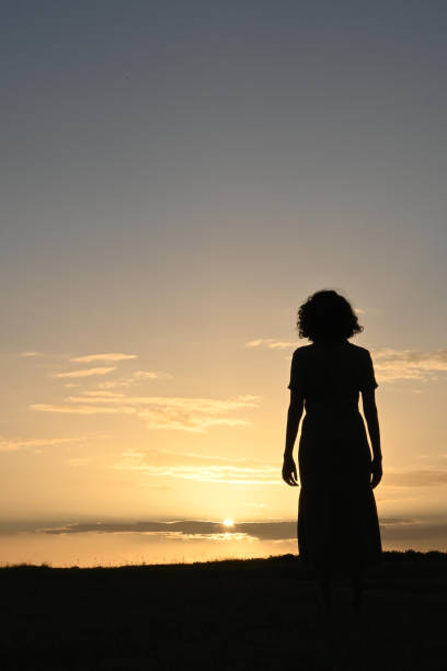 Woman alone in front of a sunrise